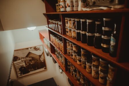 home canned foods on a pantry shelf and a historic black and white photo of an Alaskan lodge on the wall