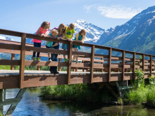 Kids on a bridge looking at a creek